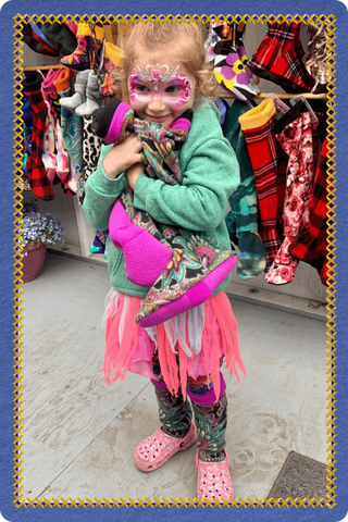 Child holding Twinkle Toes all-terrain socks at a vendor market in Palmer, Alaska