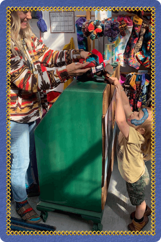 Customer shopping for Twinkle Toes socks at a vendor market in Palmer, Alaska, featuring Wild Outerwear and all-terrain socks